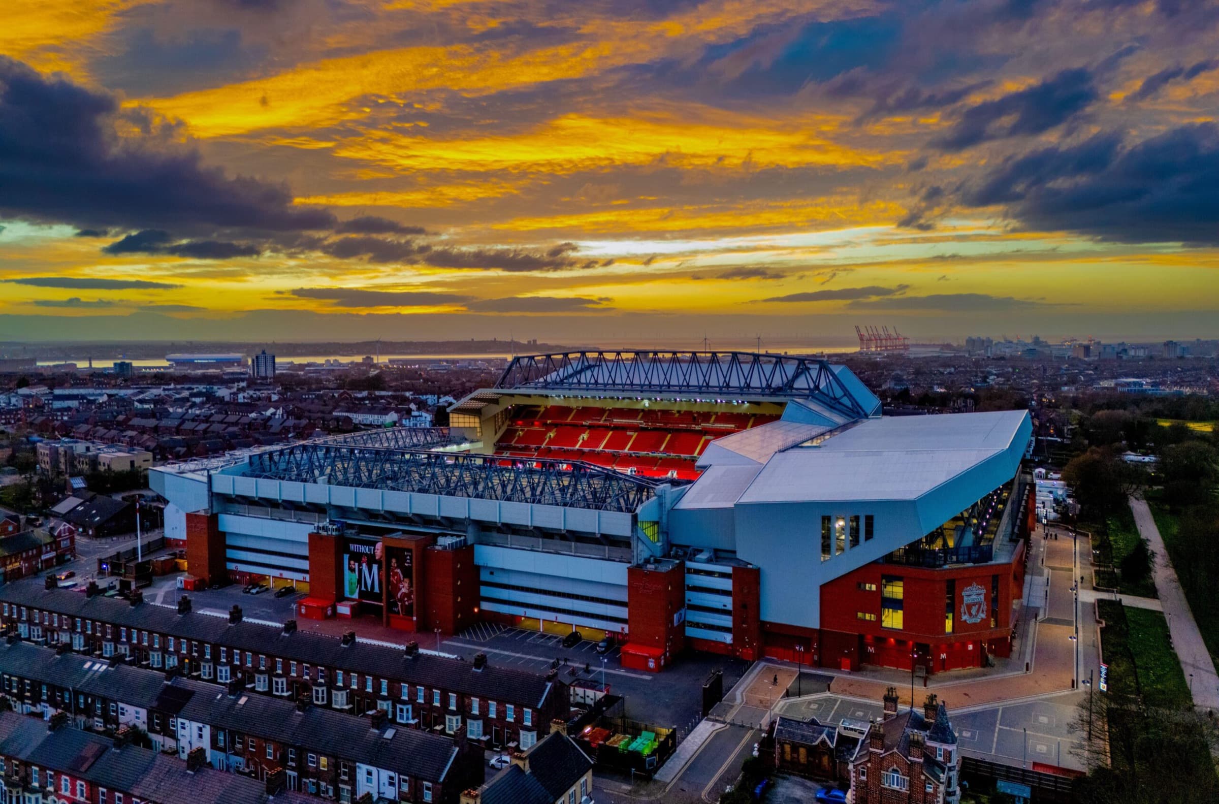 Aerial view of a football stadium at sunset, surrounded by terraced streets